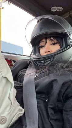 a woman wearing a motorcycle helmet sitting in a car