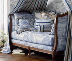 a blue and white chair sitting in front of a window with pillows on top of it