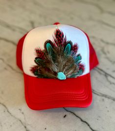 This beautiful red and white trucker hat with red, turquoise, & natural colored feathers, and a turquoise stone embellishment will be all anyone can talk about when you wear it.  It's such a fun way to spice up any outfit and the places to wear this hat are endless. Be prepared for loads of compliments.  The feathers are handpicked for each hat.  The hat has a foam front, mesh back, and an adjustable snap back. Diy Western, Colored Feathers, Shop Small Business Quotes, White Trucker Hat, Coloured Feathers, Texas Style, Hat Ideas, Ball Caps, Castle Rock