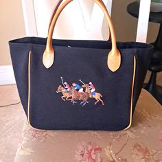 **** One Day Sale Today Sunday Dec 28 $200.00 Ralph Lauren Beautiful Embroidered Canvas And Leather Eqestrian Motif Shopping Tote In Navyblue. Beautifully Embriodered Polo Game Scene On Canvas And Leather Tote. Leather Handles And Trim. Zipper Onside Compartment And Two Slip Pockets. Beautiful Like New Condition. Measurements: Height 9inches, Width 5. 75inches, And Length Flatlay Is 14inches, Length 10inches. **** Today Sale$200 Polo Game, Ralph Lauren Equestrian, Pony Games, Ralph Lauren Bags, Polo Pony, Embroidered Canvas, Leather Handles, Shopping Tote, Leather Handle