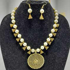 Product Description: Elevate your accessory game with the exquisite beauty of Jaipur Imitation Jewellery's Ganeshiya Brass Pendant Necklace Set. This stunning set showcases a unique Ganeshiya brass pendant suspended from a chain adorned with white pearls, offering a perfect blend of elegance and traditional charm. The pendant, meticulously crafted from high-quality brass, features a detailed depiction of Lord Ganesha, the revered Hindu deity. The intricate craftsmanship brings out the divine ess Brass Pendant Necklace, Lord Ganesha, Brass Pendant, Multi Strand Necklace, Pearl Chain, Strand Necklace, Contemporary Fashion, Multi Strand, Ganesha