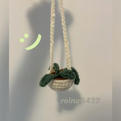 there is a small hanging planter made out of rope with a green leaf on it