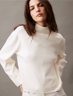 Woven with a half milano knit, this sweater is styled with long sleeves and a mock neck. Designed with drop shoulders for a relaxed fit. Created with simple, solid styling for a modern look.  Material: 72% Viscose, 28% Polyester. Spring Turtleneck Sweater, Modern Fine Knit Turtleneck Sweater, Winter Mock Neck Top For Layering, White Long Sleeve Turtleneck For Work, Winter White Turtleneck Tops For Fall, Classic Textured Knit Stretch Sweater, Classic Stretch Sweater With Textured Knit, Classic Spring Turtleneck Sweater, Classic Turtleneck Sweater For Spring