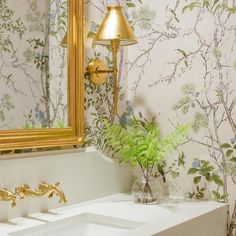 a white sink sitting under a mirror next to a gold framed mirror on a wall