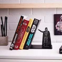 some books are sitting on a shelf next to a star wars figurine and other items