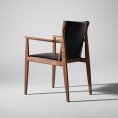 a wooden chair with black leather upholstered seat and armrests on a white background