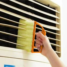 a person is cleaning the air conditioner with a brush