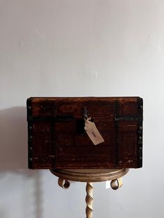 an old wooden chest sitting on top of a table with a tag hanging from it