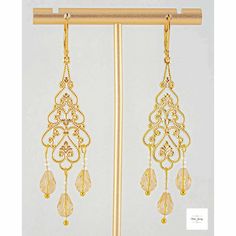 Add some radiance and enchantment to your style with these stunning yellow champagne filigree earrings! The sparkling yellow champagne-colored glass teardrop beads are perfectly accented by shimmery white glass beads, all set in intricate gold-plated filigree and lever backs. These dangling earrings, measuring 2.75 inches, will definitely catch attention. Elevate any ensemble with these gorgeous yellow glass and gold filigree earrings. Yellow Champagne, Amarillo Color, Gold Filigree Earrings, Long Gold Earrings, Boho Chic Jewelry, Filigree Earrings, Yellow Earrings, Teardrop Beads, Gemstone Jewelry Handmade