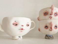 three white mugs with faces painted on them