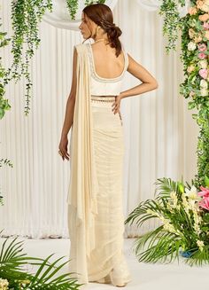 Featuring an ivory-hued shimmer georgette pre-draped saree paired with a U-neckline bustier detailed with pearl, bead, and sequin work. The look is finished with an embellished long cape featuring pearl tassels and a belt. This ensemble is a ready to wear saree for your ease ! Composition : Saree: Georgette, Blouse: Silk, Cape & Belt: Crepe Care: Dry Clean Only and Vacuum Storage All products can be customised for sleeves, length of blouse and neck design Delivery : 4-6 weeks as the product is h Hand Embellished Georgette Pre-draped Saree For Reception, Designer Georgette Cream Pre-draped Saree, Off White Georgette Pre-draped Saree For Reception, Silk Pre-draped Saree With Pearl Embroidery For Reception, Party Wear Pre-draped Saree With Pearl Embroidery For Reception, Party Silk Pre-draped Saree With Pearl Embroidery, Glamorous Fitted Pre-draped Saree With Pearl Embroidery, Designer Pre-draped Fitted Saree With Pearl Embroidery, Designer Pre-draped Pearl Embroidered Saree