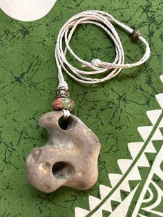 a piece of pottery is laying on a green tablecloth with a white beaded cord