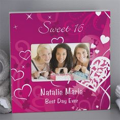 a pink frame with hearts and two girls in the center is next to a teddy bear