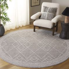 a living room area with a chair, rug and potted plant on the floor