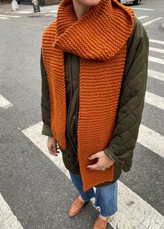 a woman standing on the street wearing an orange scarf