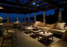 an outdoor living area with couches, tables and lamps on the patio at night