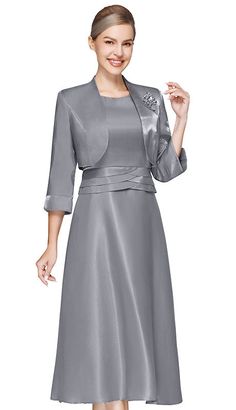 Introducing the Nina Nischelle 3623-GRY Jacket Dress, a true embodiment of sophistication and timeless style. This ensemble is meticulously crafted to create an air of elegance for any upscale event. The knee-length dress speaks to the essence of classic femininity, making it a perfect choice for weddings, corporate gatherings, or formal celebrations. The luxurious, shimmering grey fabric of the dress is carefully selected for its quality and luster, ensuring that you sparkle with understated elegance. A highlight of this dress is the three-quarter sleeve jacket that elegantly drapes over the shoulders. It is adorned with an exquisite brooch that adds a focal point of glamour to the overall attire, capturing the attention of onlookers without the need for additional accessories. Attention Elegant Tailored A-line Outerwear, Elegant Satin A-line Mother Of The Bride Dress, Elegant A-line Formal Outerwear, Elegant A-line Evening Dress For Winter, Fall Evening Dress With Fitted Bodice, Elegant Tailored Jacket Dress For Party, Tailored Elegant Jacket Dress For Party, Winter Formal A-line Evening Dress, Elegant Evening Jacket Dress For Spring