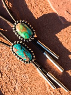 three turquoise and silver colored objects laying on the ground next to each other with black beads