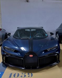 a blue bugatti is parked in a garage with two other cars behind it