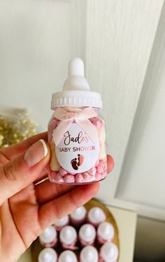 a hand holding a baby shower jar filled with pink and white candies