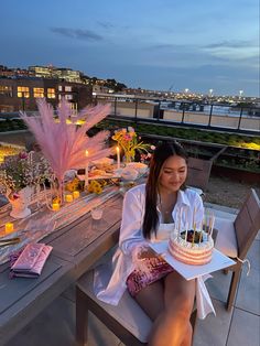 a woman sitting at a table with a cake and candles on it in front of her