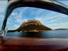 a boat traveling on the water with a mountain in the background