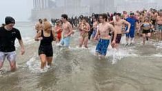 many people are running in the water at the beach