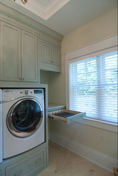 a washer and dryer in a room with white cabinets on either side of the window