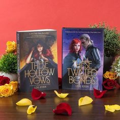 two paperback books sitting on top of a wooden table next to flowers and potted plants