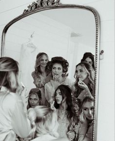 a group of women standing in front of a mirror