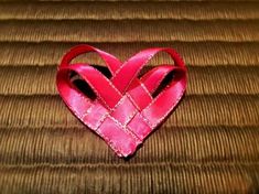 a pink heart shaped ribbon sitting on top of a bed