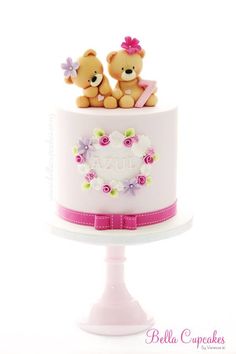 two teddy bears sitting on top of a cake