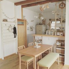 a table and chairs in a room with wooden floors, white walls and wood flooring