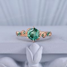 a ring with an emerald colored stone in the center and two green stones on each side