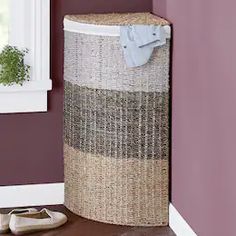 a laundry hamper sitting next to a window in a room with purple walls and wooden floors