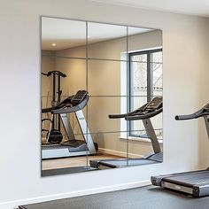 an exercise room with mirrors and treadmills