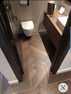 a bathroom with wood flooring and white toilet next to a sink in the corner