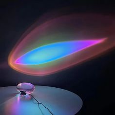 a colorful object sitting on top of a white table next to a black wall with light coming from it