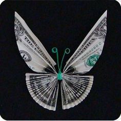 a butterfly made out of money sitting on top of a black surface