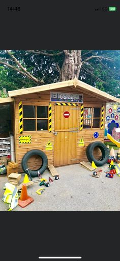 there is a small wooden play house with tires on the ground and construction equipment around it