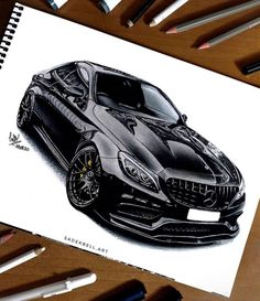 a drawing of a black sports car on top of a table with markers and pencils