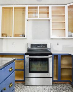 an empty kitchen with blue cabinets and stainless steel stove top oven in the middle,