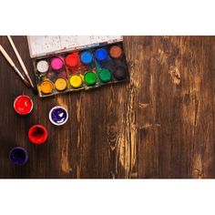 an artist's palette, paint and brushes on a wooden table with watercolors