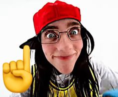 a woman with long hair wearing glasses and a red hat is making the peace sign