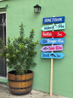 a wooden sign sitting on the side of a building next to a potted plant