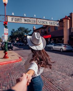 a woman holding the hand of a man in front of fort worth stock yards