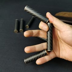 a hand holding three black metal objects on top of a dark surface with other items in the background