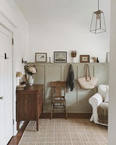 a living room with a chair, table and pictures on the wall above it's door