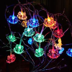 a lighted tree with many colorful lights on it's branches and flowers in the center