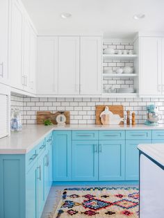 a kitchen with blue cabinets and white counter tops is pictured in this image, the area rug has been placed on the floor